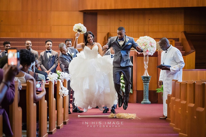 Couple jumping over a broom during wedding ceremony