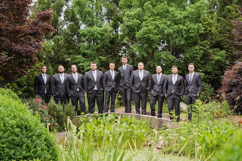 Groom and groomsmen standing in a garden on his wedding day.