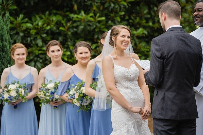 The groom reciting his vows to his bride while her bridesmaids look on.