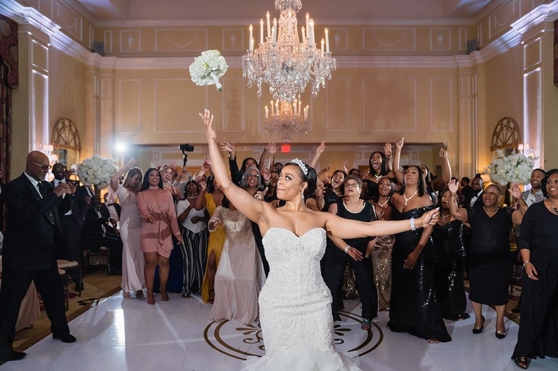 A bride throws her bouquet in the air at her wedding reception.
