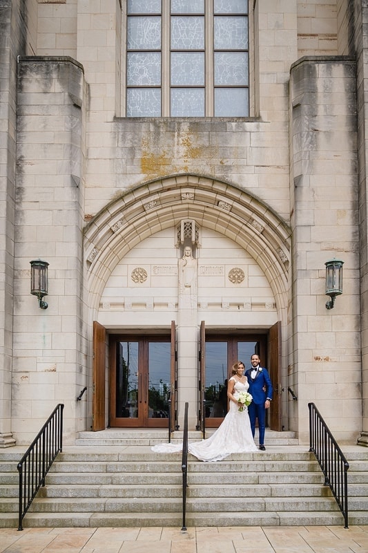 A stunning wedding couple posing on the steps of a church.
