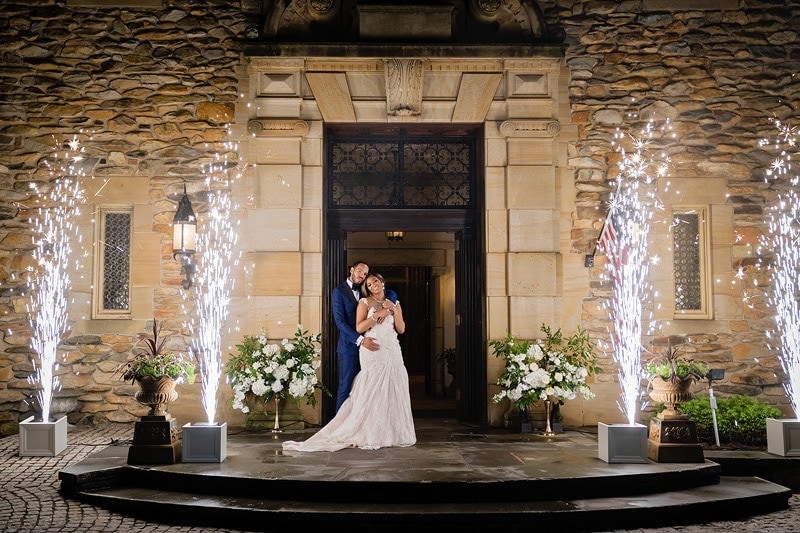 Wedding photographers capture a stunning moment of a bride and groom, illuminated by sparklers, against the enchanting backdrop of a castle.