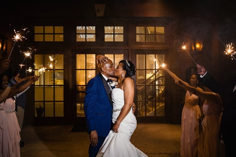 Wedding photographers capturing a breathtaking moment of a bride and groom kissing in front of sparklers.
