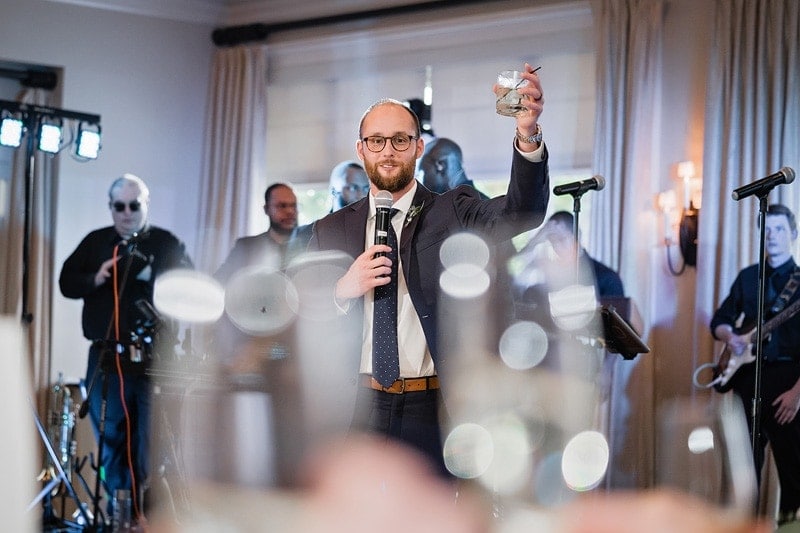 A man holding a glass giving a toast during the wedding reception.