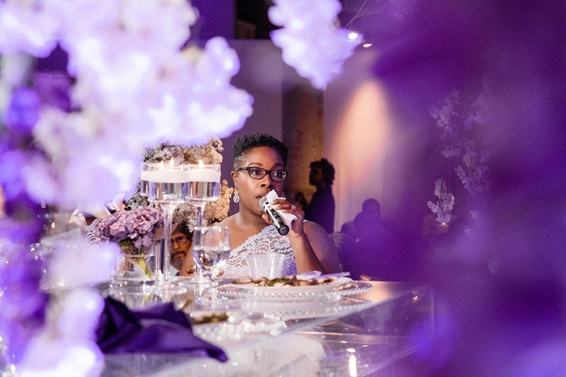 A bride is speaking at a wedding reception, captured by wedding photographers.