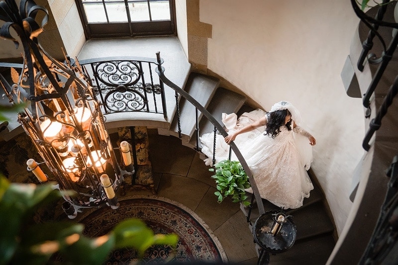 Capture a stunning moment of a bride gracefully descending a staircase in her exquisite wedding dress, beautifully composed by talented wedding photographers.