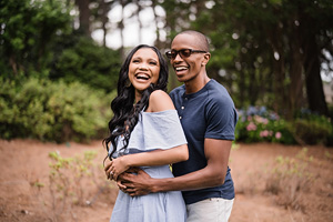 Engagement photography: A black couple embracing in the woods during their engagement session.