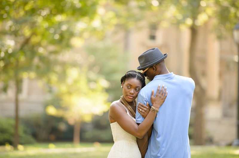 A man and woman capturing their love through engagement photography in a park, sharing a heartfelt hug.