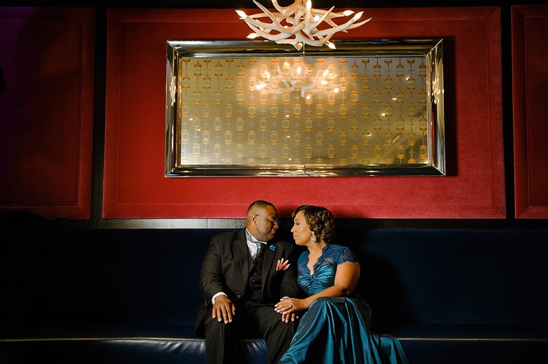 A man and woman posing for engagement photos on a blue couch.