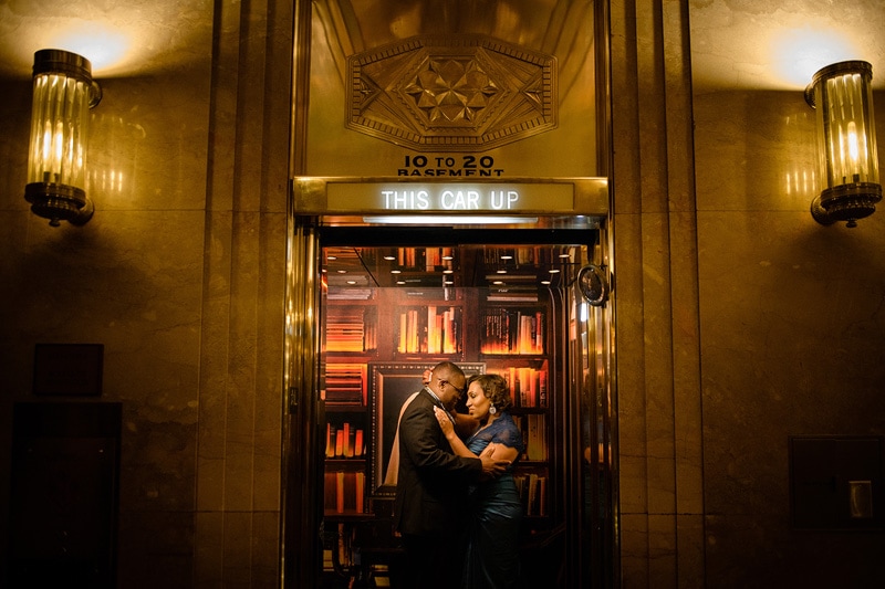 A couple shares an intimate moment in the elevator, captured by an engagement photographer.