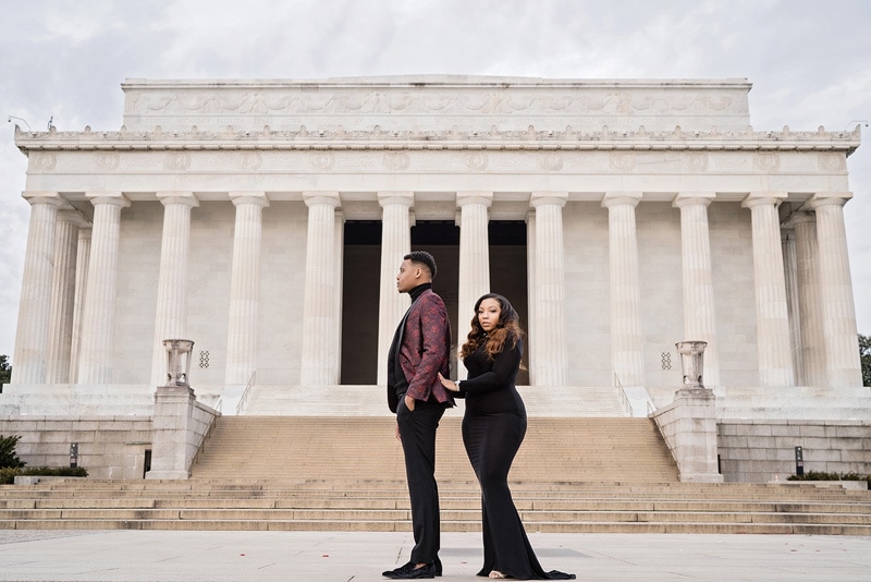 An engaged couple standing in front of the Lincoln Memorial, captured beautifully by an engagement photographer.
