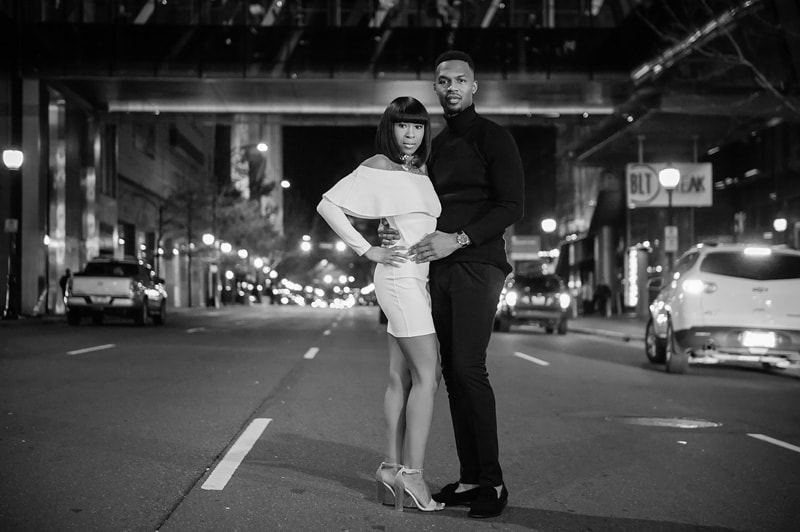 An enchanting black and white engagement photo of a couple beautifully posing in the nighttime city streets.
