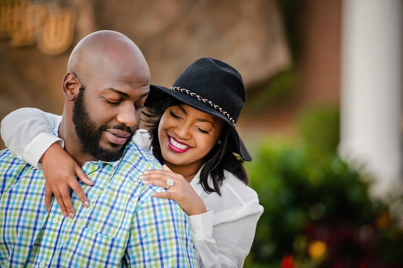 An engaged black couple hugging in front of a building.