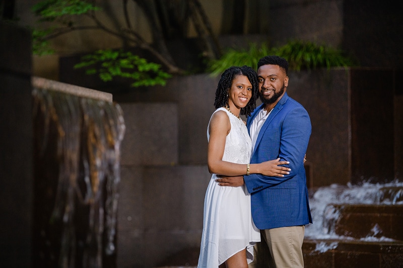 An engaged couple captured in stunning engagement photos by a talented engagement photographer, gracefully posing in front of a majestic fountain.