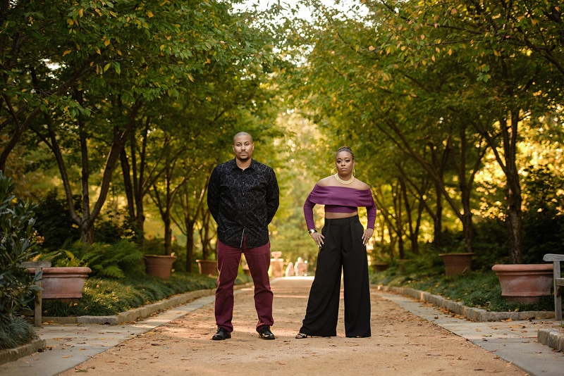 An engagement photographer captures the blissful couple as they stand on a path in a park, creating stunning engagement photos through their expert engagement photography skills.