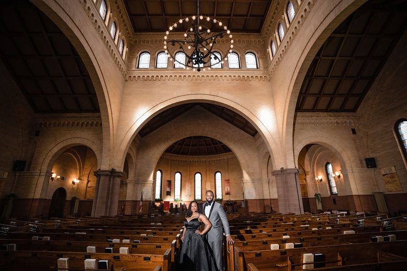 An engaged couple standing in the middle of a church, captured by an engagement photographer.