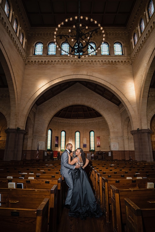 An engagement photographer captures the intimate moment of a bride and groom embracing in a church, creating beautiful engagement photos.