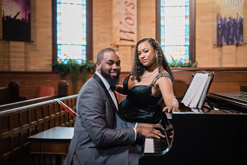 A man and woman performing on a piano in a church captured by an engagement photographer.