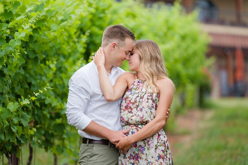 A couple enjoys their engagement session in front of a beautiful vineyard, captured by an engagement photographer.