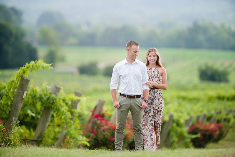 An engaged couple posing for engagement photos in a vineyard, captured by an engagement photographer.