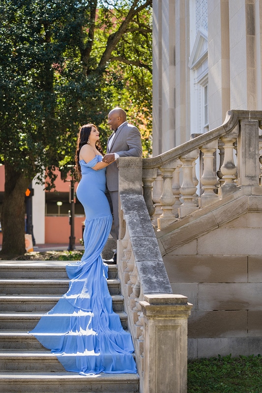 An engagement photographer captures a bride and groom as they pose on the steps of a building, creating beautiful engagement photos.