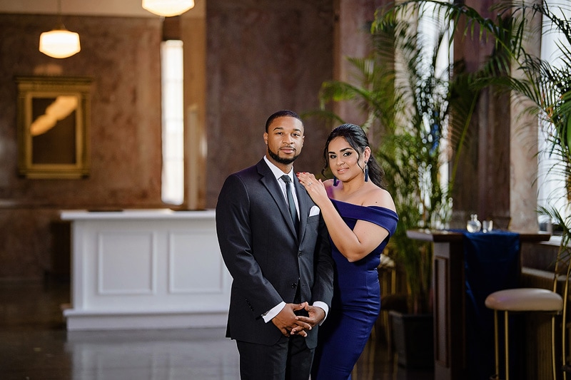 An engaged couple posing for engagement photos in a lobby, captured by an engagement photographer.