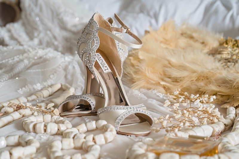 A bride's wedding shoes from the distillery wedding are laying on a bed.