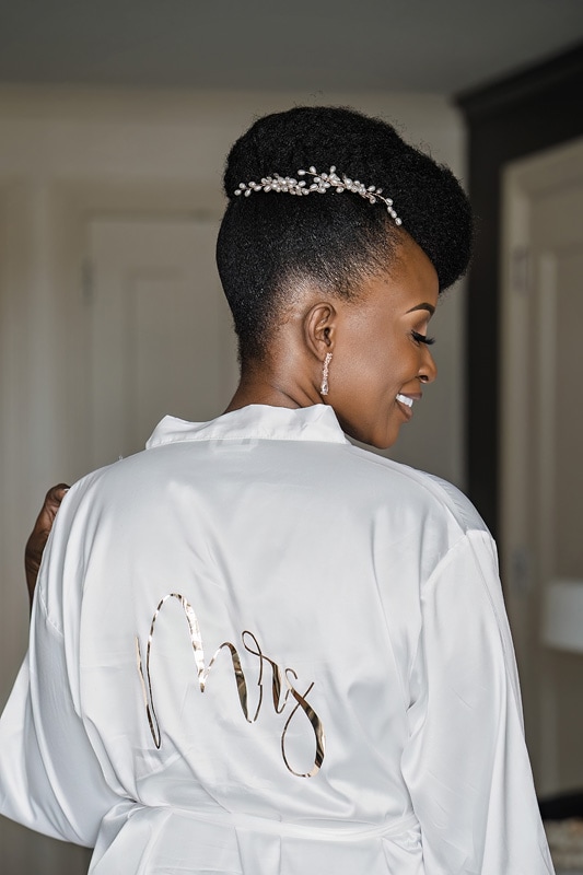 A woman wearing a robe with the word "Mrs." on it, getting ready for her wedding at the distillery.