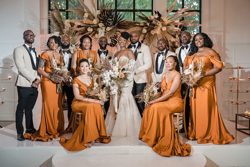 The Distillery wedding party in orange tuxedos posing for a photo.