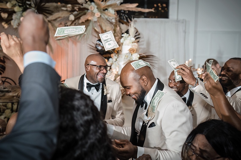 A group of men with money in their hands at a distillery wedding.