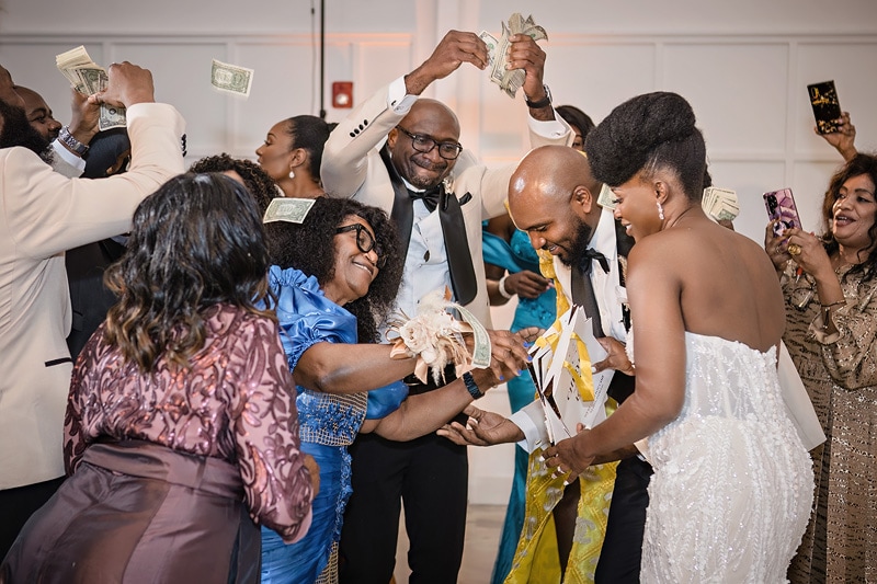 A group of people holding money in their hands at the distillery wedding.