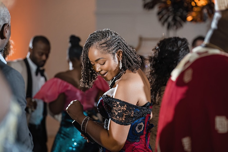 A woman in an African dress dancing at a party, the distillery.