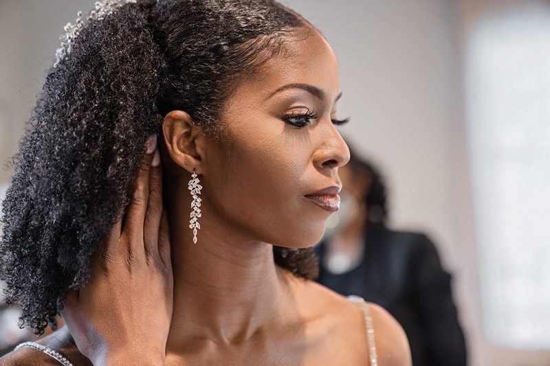 A bride getting ready for her Board and Batten Wedding, putting on her earring.