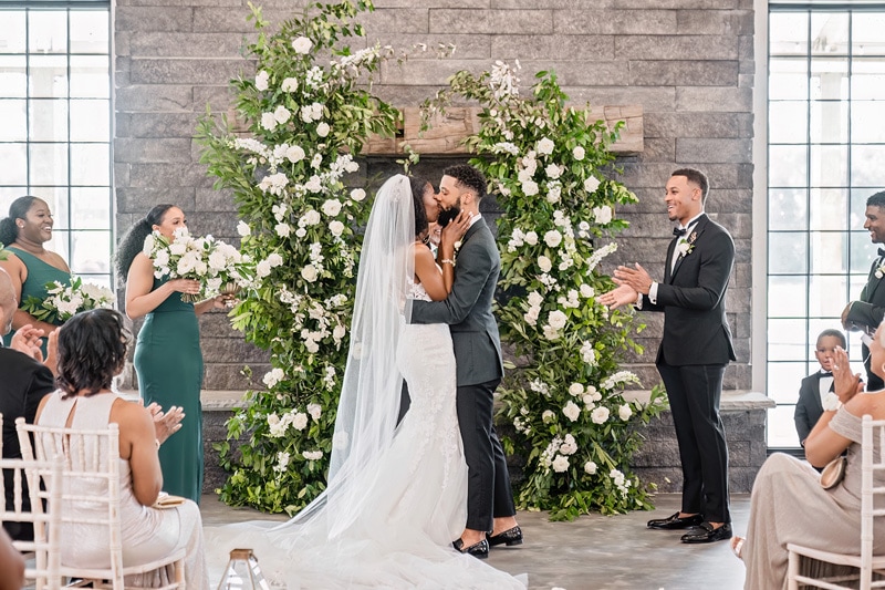 During their "Board and Batten Wedding" ceremony, the groom and bride share a tender kiss.