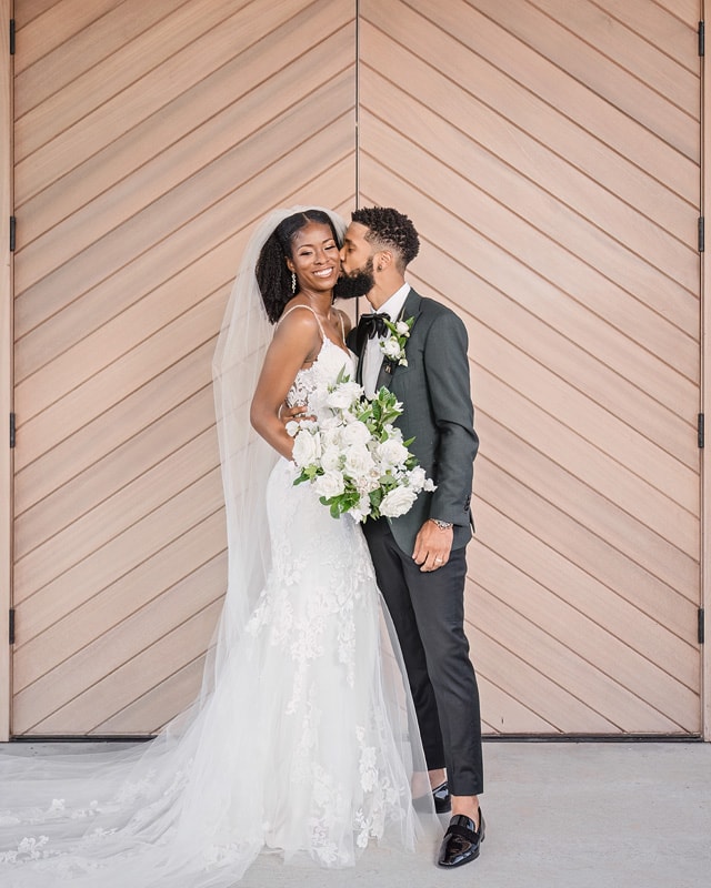 A bride and groom kissing in front of a Board & Batten Wedding door.