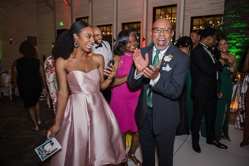 A man and woman joyfully clap at a Board & Batten Events wedding reception.