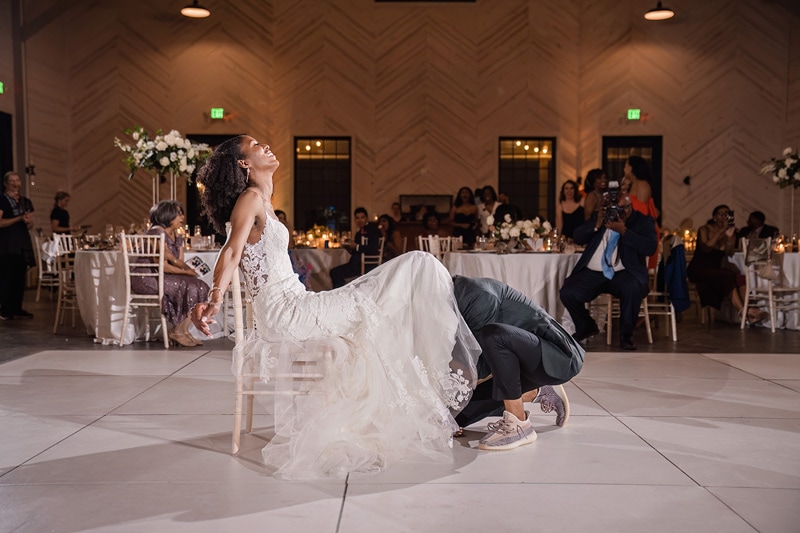 A bride and groom dancing on a chair at a Board & Batten Events Wedding reception.