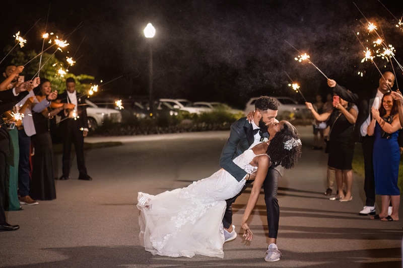 Incorporating sparklers, a bride and groom share a kiss at their Board & Batten Events wedding.