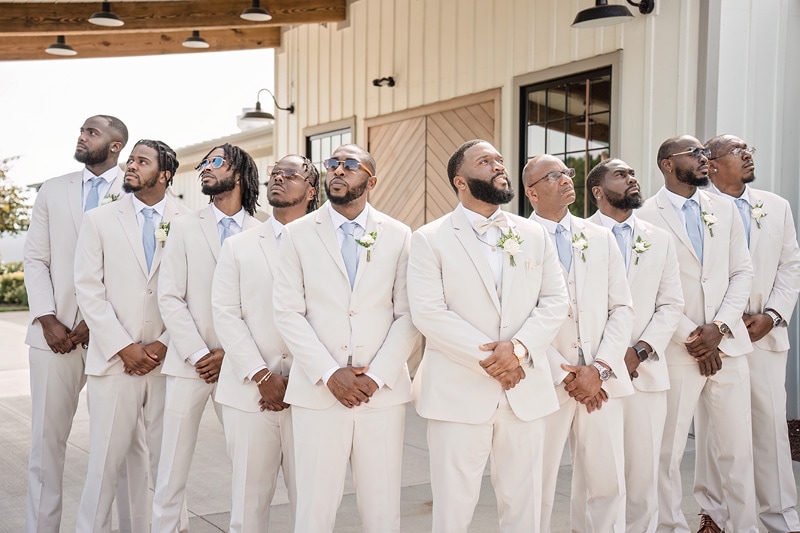 A group of groomsmen standing in front of Board & Batten Events wedding venue.