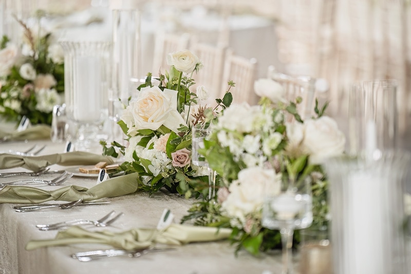 At Board & Batten Events, a long table is elegantly set with white flowers and silverware.