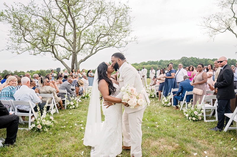 A bride and groom share a kiss at their outdoor wedding ceremony at Board and Batten Wedding Venue in NC.