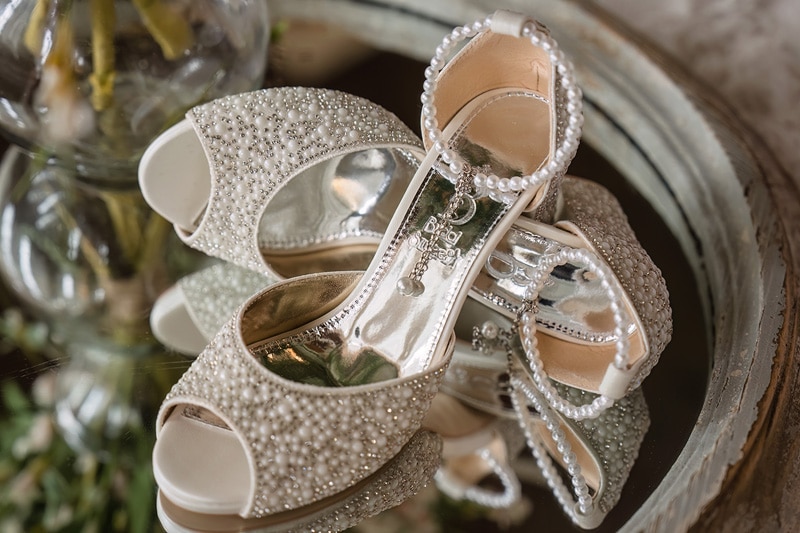 A pair of Pinehill Pavilion wedding shoes sitting on a mirror.