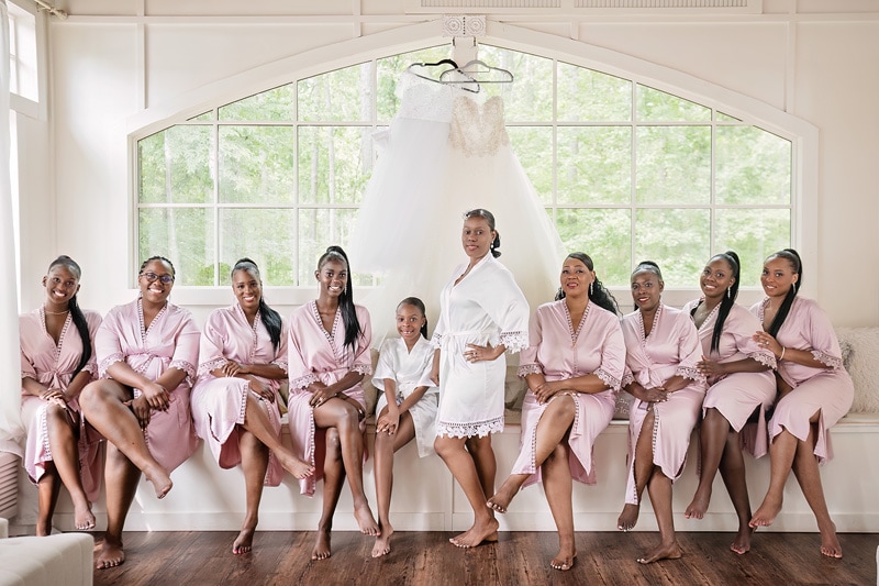 At the Pinehill Pavilion Wedding, a group of bridesmaids in pink robes gather together, elegantly posing for a photo.