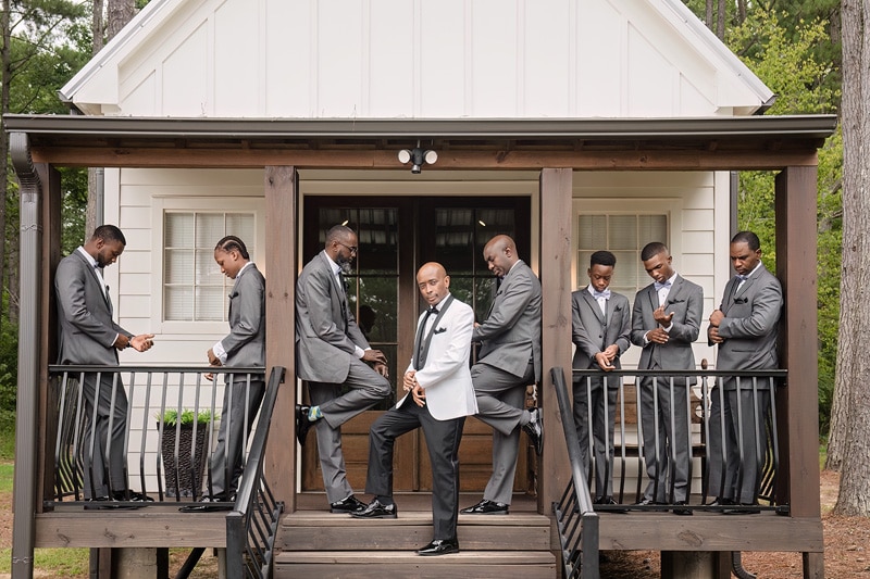 A group of groomsmen standing on the porch of the Pinehill Pavilion cabin.