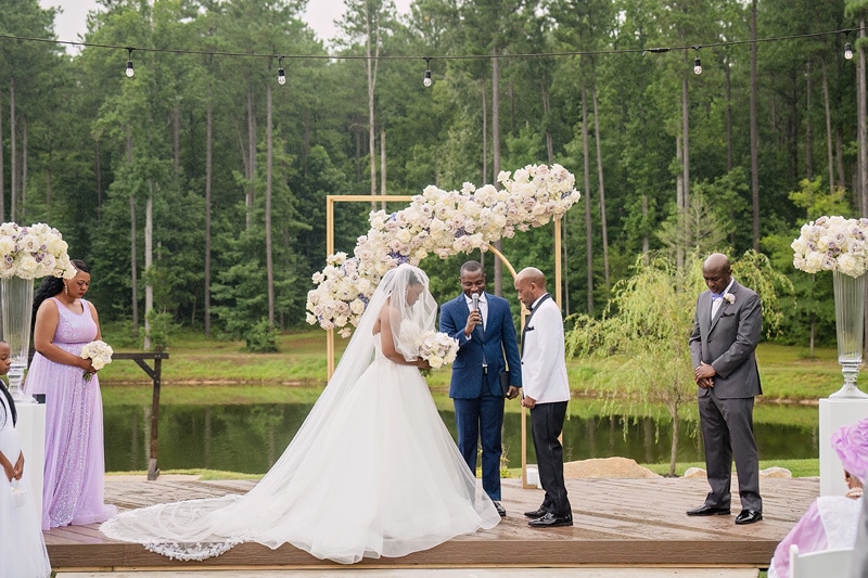 A Pinehill Pavilion wedding with a bride and groom under a floral arch.
