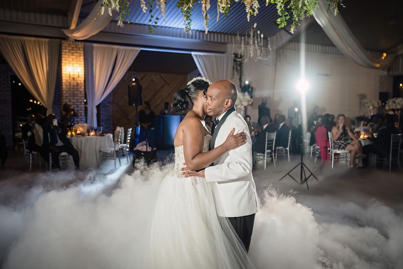 A bride and groom sharing a romantic kiss in a cloud of smoke at their Pinehill Pavilion wedding reception.