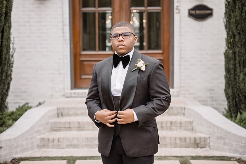 A man in a tuxedo standing in front of The Bradford wedding venue.