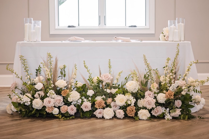 A white table with flowers and candles on it at The Bradford wedding venue.