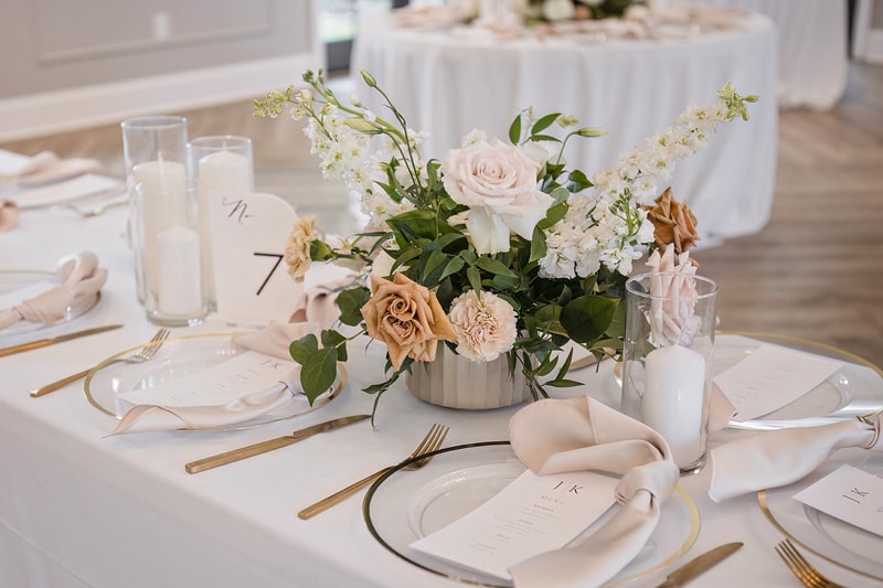 A white table setting with white flowers and gold plates at The Bradford wedding venue.