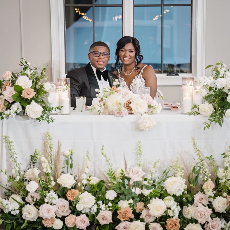 A man and woman sitting at a table with flowers at The Bradford wedding venue.